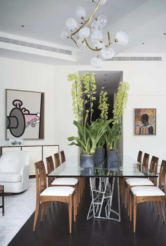 Picture of a dining room table with vases of flowers and a chandelier