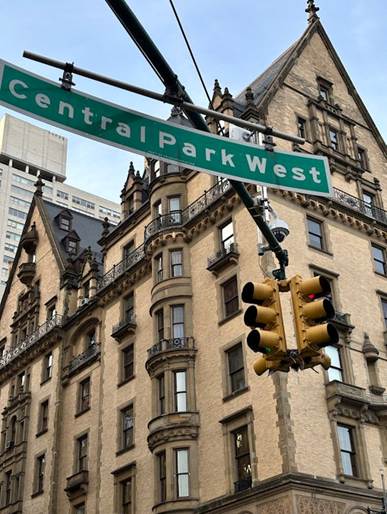 A picture of a street sign reading "Central Park West" in the foreground with a beautiful apartment building in the background