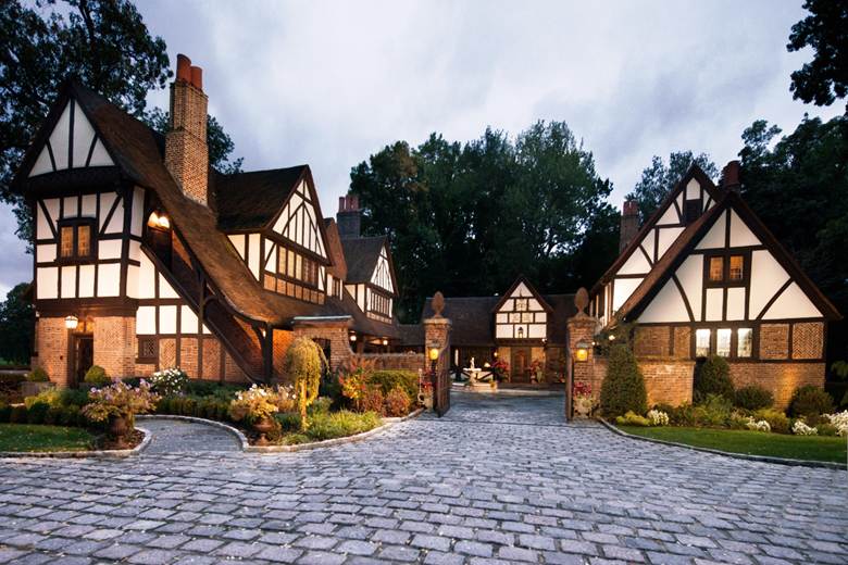A picture of a home in the background in front of a cobblestone driveway